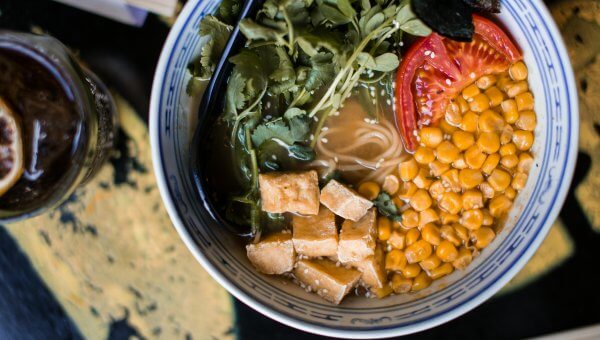 bowl of vegan ramen with tofu, corn, tomato, herbs