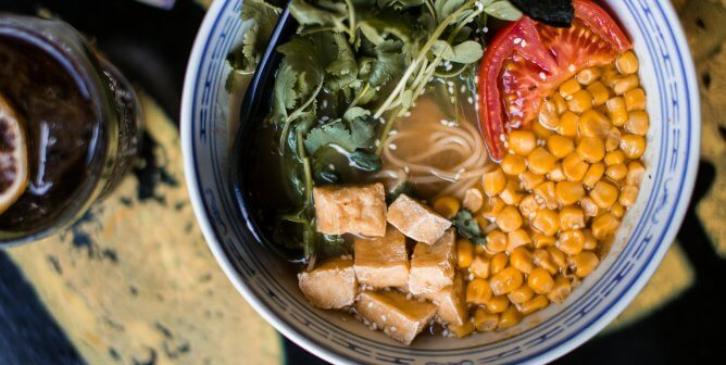 bowl of vegan ramen with tofu, corn, tomato, herbs