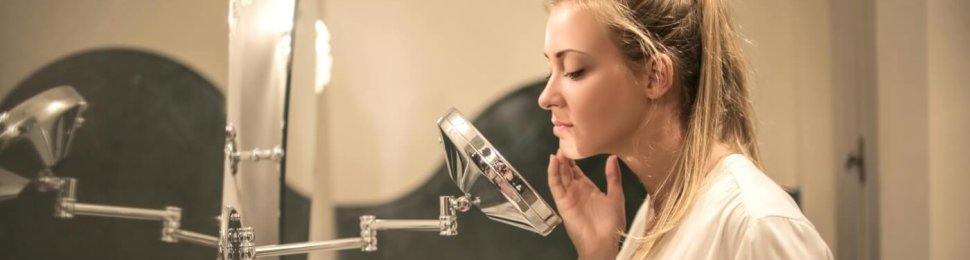 woman looking at her skin in a mirror