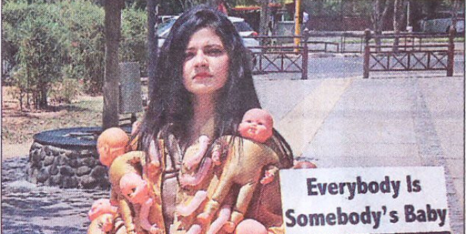 woman in coat covered in plastic babies walks the streets