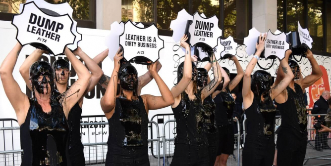 protesters in all black dump "toxic" waste on thiemselves to encourage people to dump leather