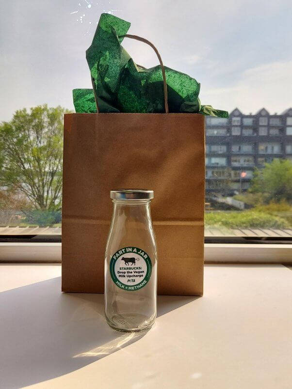 gift bag behind a mock Starbucks bottle containing a cow fart that PETA sent to the coffee giant's CEO for Earth Day