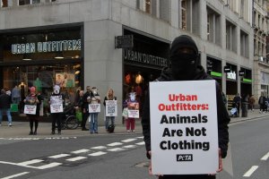 protestors stand outside urban outfitters in London with signs