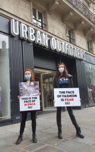 Protestors in Paris stand outside of Urban Outfitters with signs