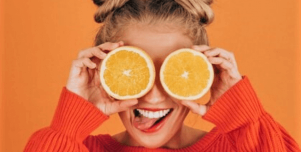 woman with space buns holding oranges as eyes