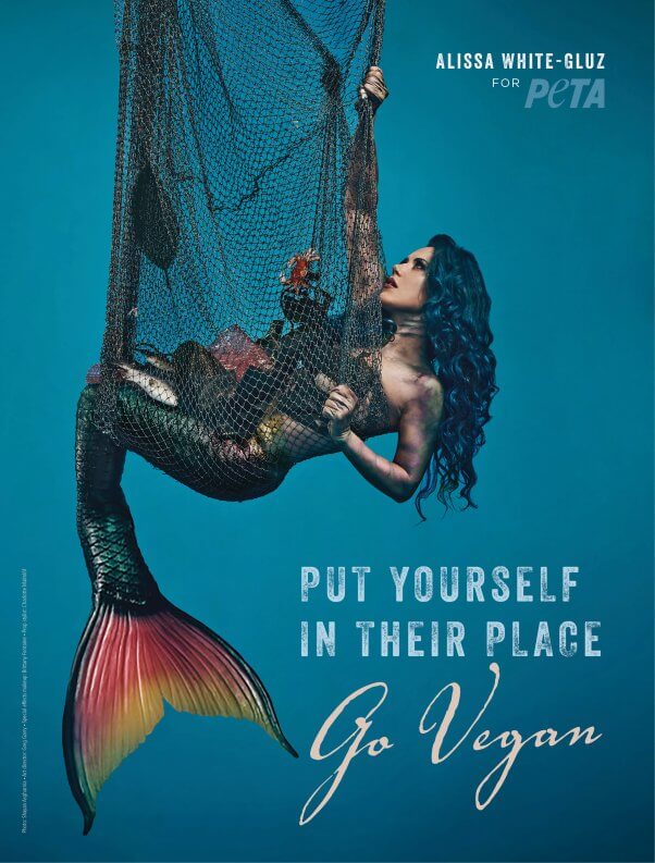 alissa white-gluz dressed as a mermaid caught in a net for a PETA ad