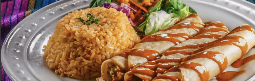 a plate with two vegan taquitos, mexican rice, and salad
