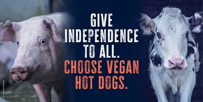 Cow and pig on dark blue background with white and orange text that says "Give Independence to all. Choose vegan hot dogs."