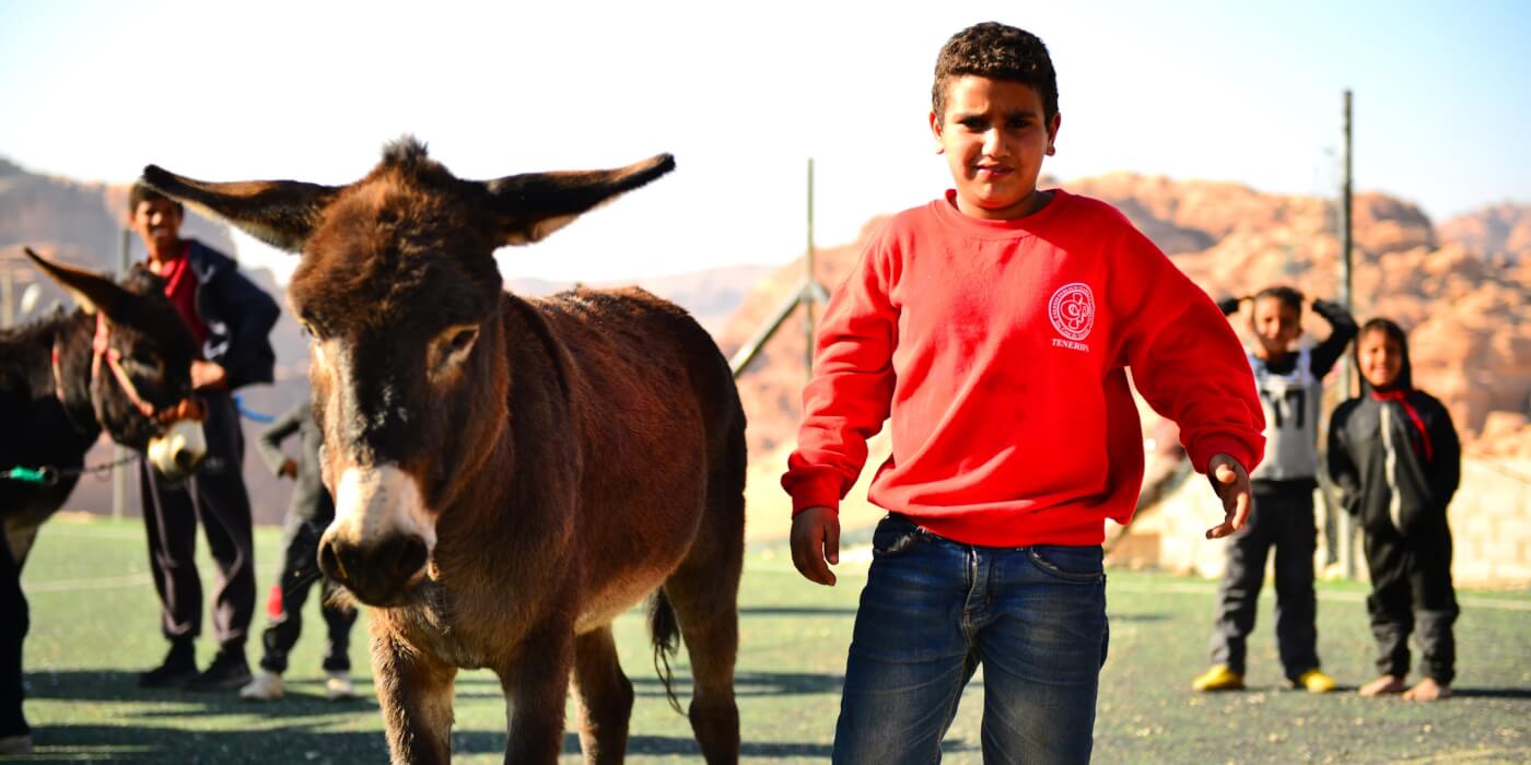 Boy in Petra stands next to a donkey