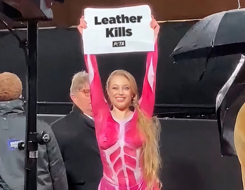 PETA supporter in muscle body suit holds sign at London Fashion Awards