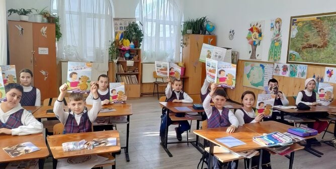 Schoolchildren in Romania hold up books