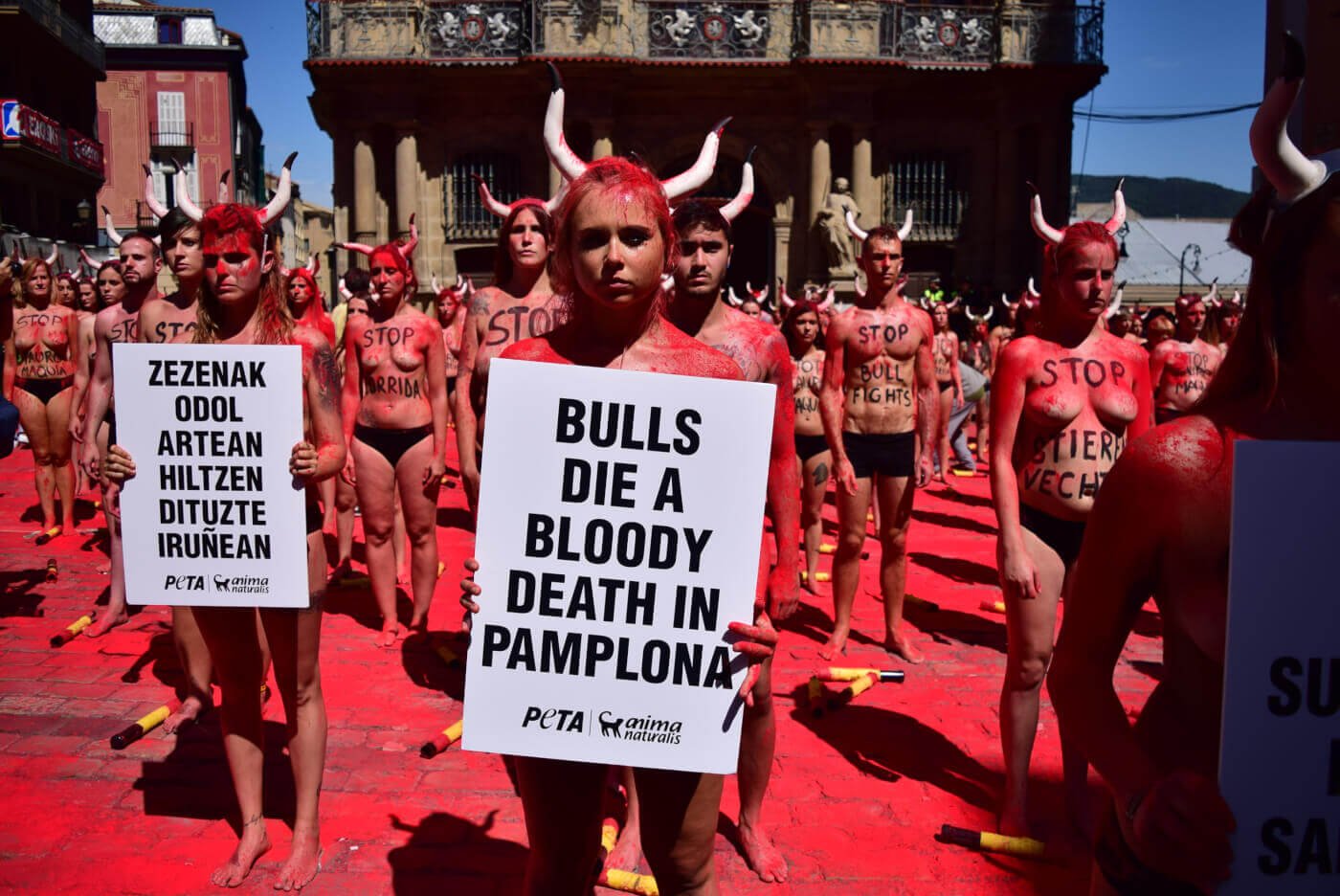 Nearly naked protestors covered in fake blood wearing bull horns
