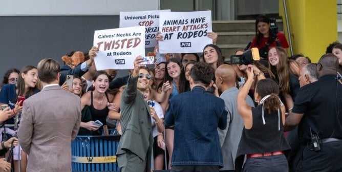 Glen Powell Taking a selfie with PETA Protestors against the Rodeo Scene in Twisters