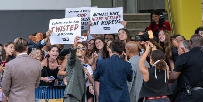 Glen Powell Taking a selfie with PETA Protestors against the Rodeo Scene in Twisters