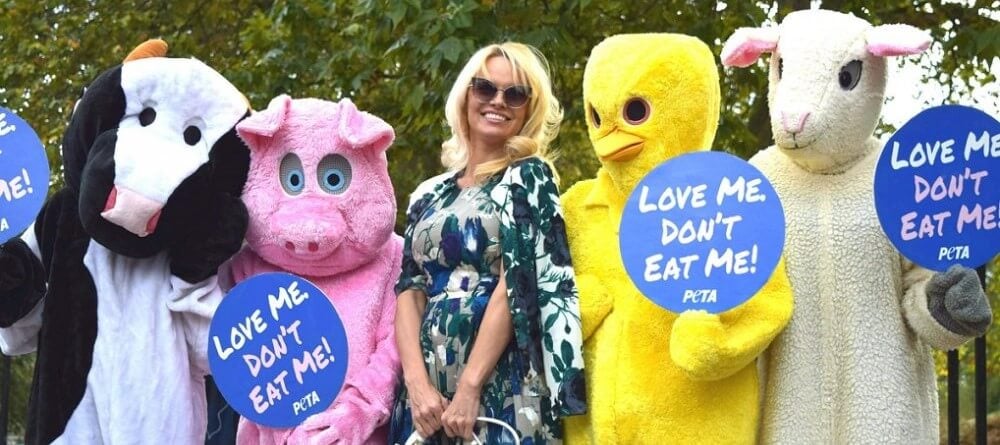 Pamela Anderson stands with protestors who are dressed as animals exploited in the food industry