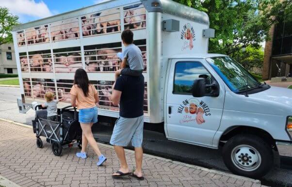 A family walking past the Hell on Wheels pig truck