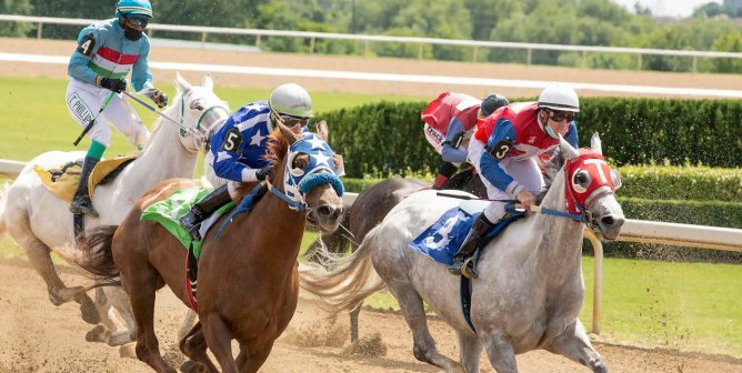 humans riding horses in race on dirt path