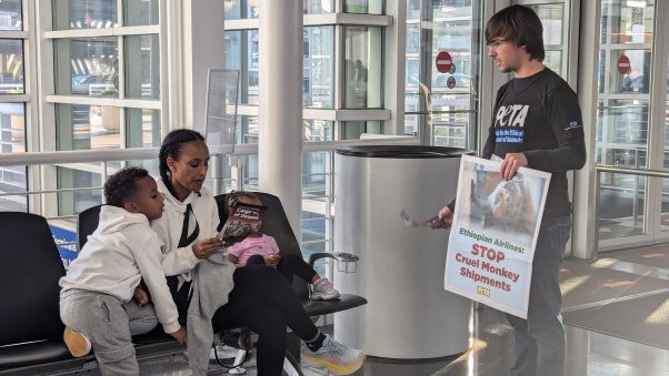 PETA Supporter with a poster sign speaks with two passerbys at the Ohare airport