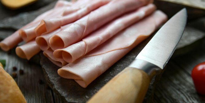 deli meat on cutting board with a knift