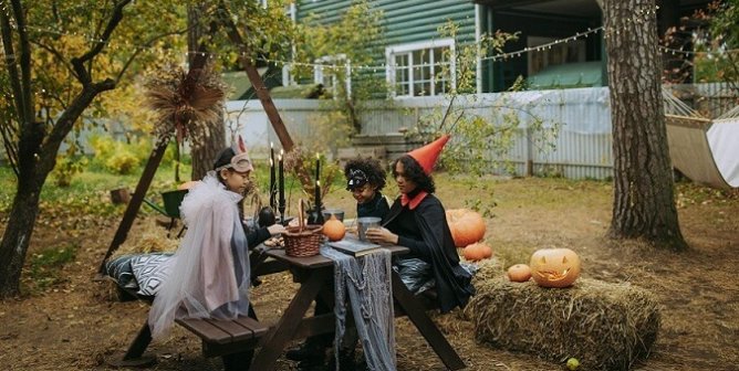 Kids making Halloween ornaments outside their house at a picnic table.