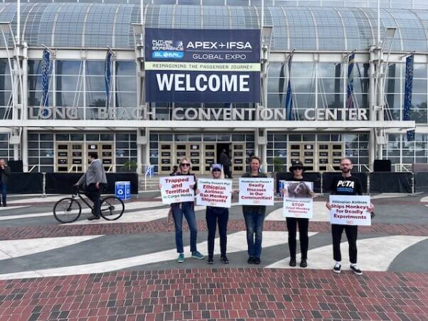 Demonstrators holding signs in front of the Long Beach Convention Center