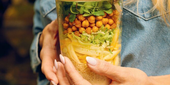 Pamela Anderson holding a mason jar filled with salad