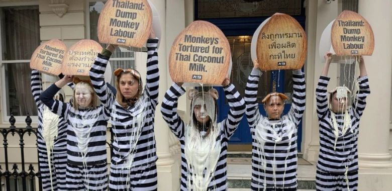 A group of people in prison outfits dousing themselves in 'coconut milk'