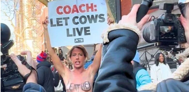 A woman holding up a sign that says Coach: Let Cows Live