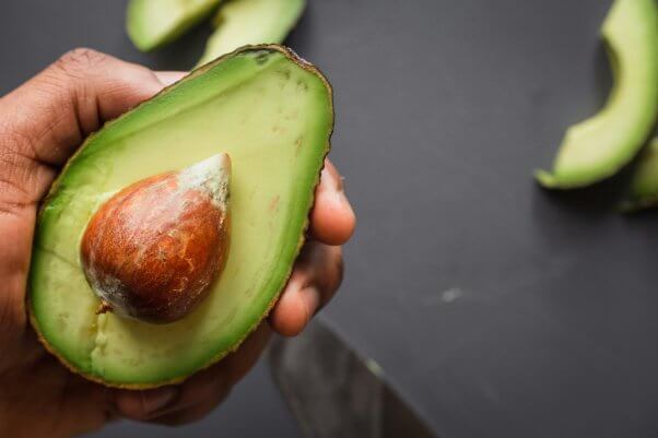 A person holding a halved avocado