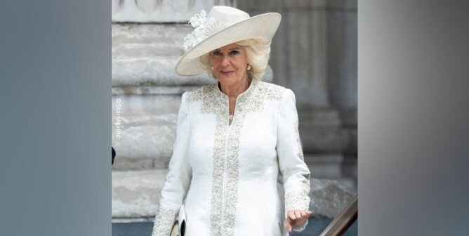 queen camilla in white dress and hat walking down stairs